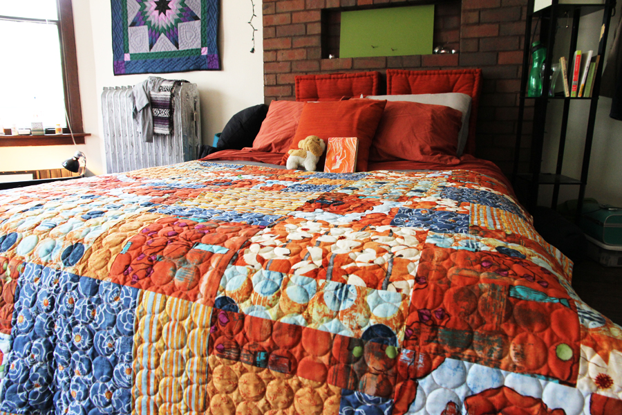 red and blue poppy patterned quilt with circle finishing stitching on a queen sized bed