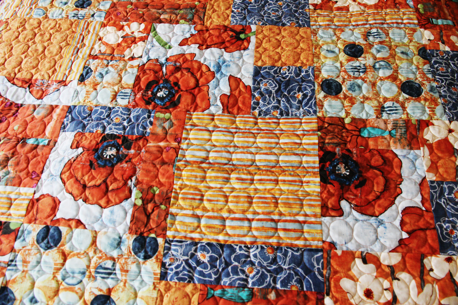 red and blue poppy patterned quilt with circle finishing stitching red and blue poppy patterned quilt with circle finishing stitching